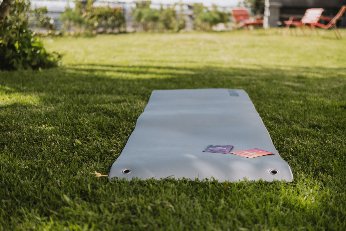 Sachets patches sur un tapis de yoga gris, en extérieur dans un jardin ensoleillé.